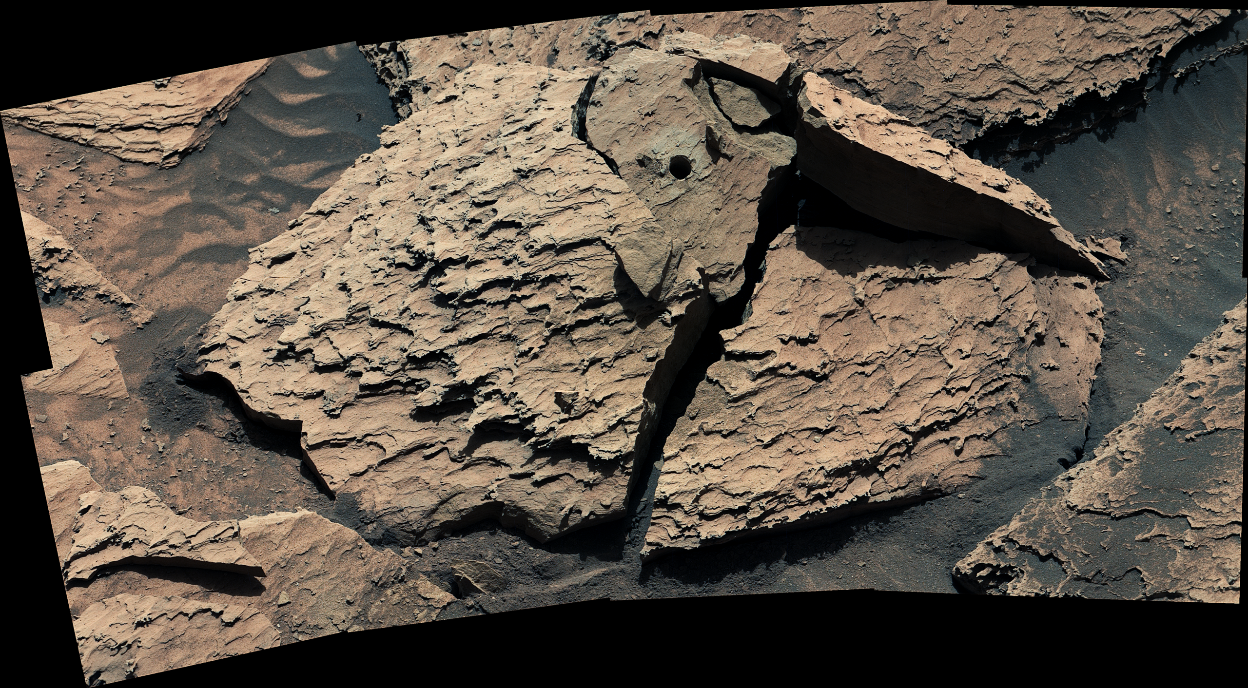 A large, reddish-brown rock as seen by NASA's Curiosity Mars rover. The rock is broken into sever...