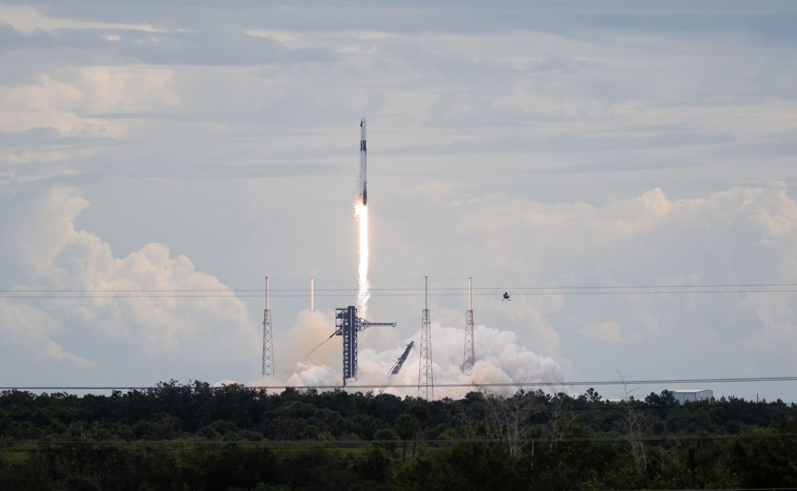 A SpaceX Falcon 9 rocket carrying the company's Dragon spacecraft launches. There is a bright col...