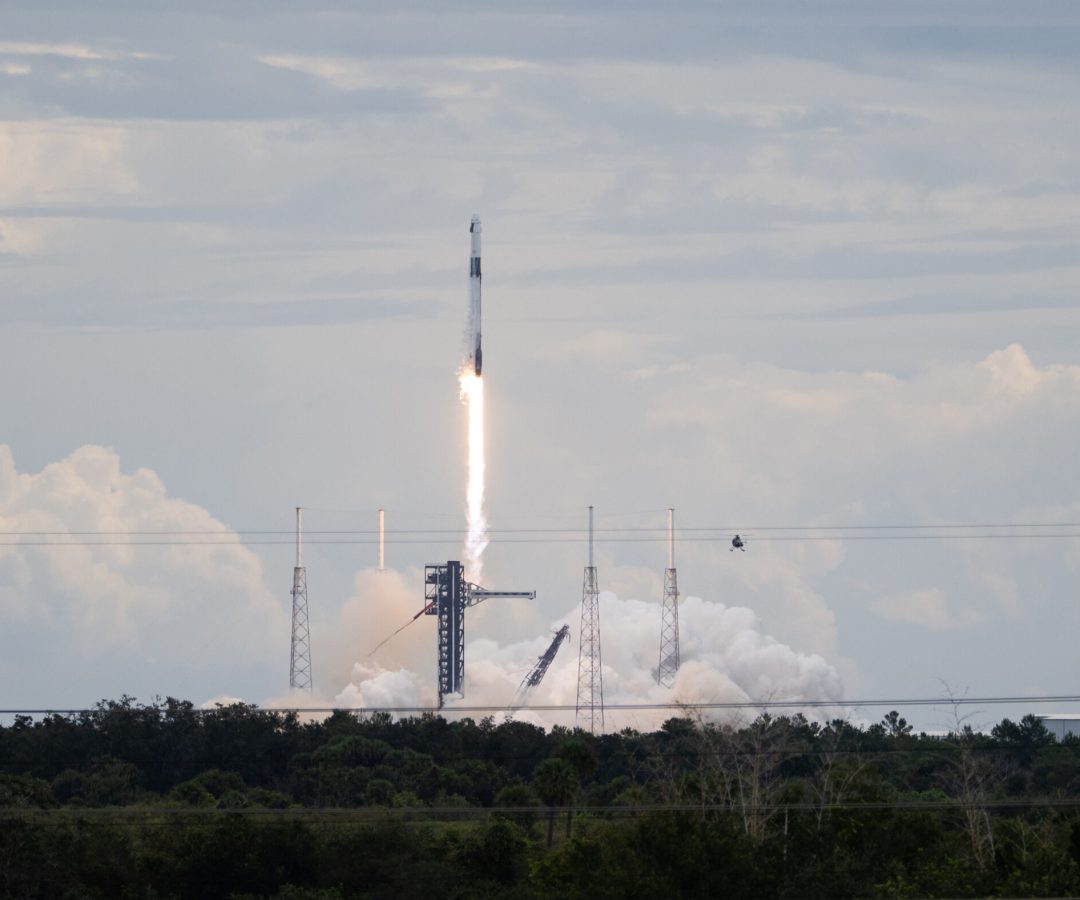 A SpaceX Falcon 9 rocket carrying the company's Dragon spacecraft launches. There is a bright col...