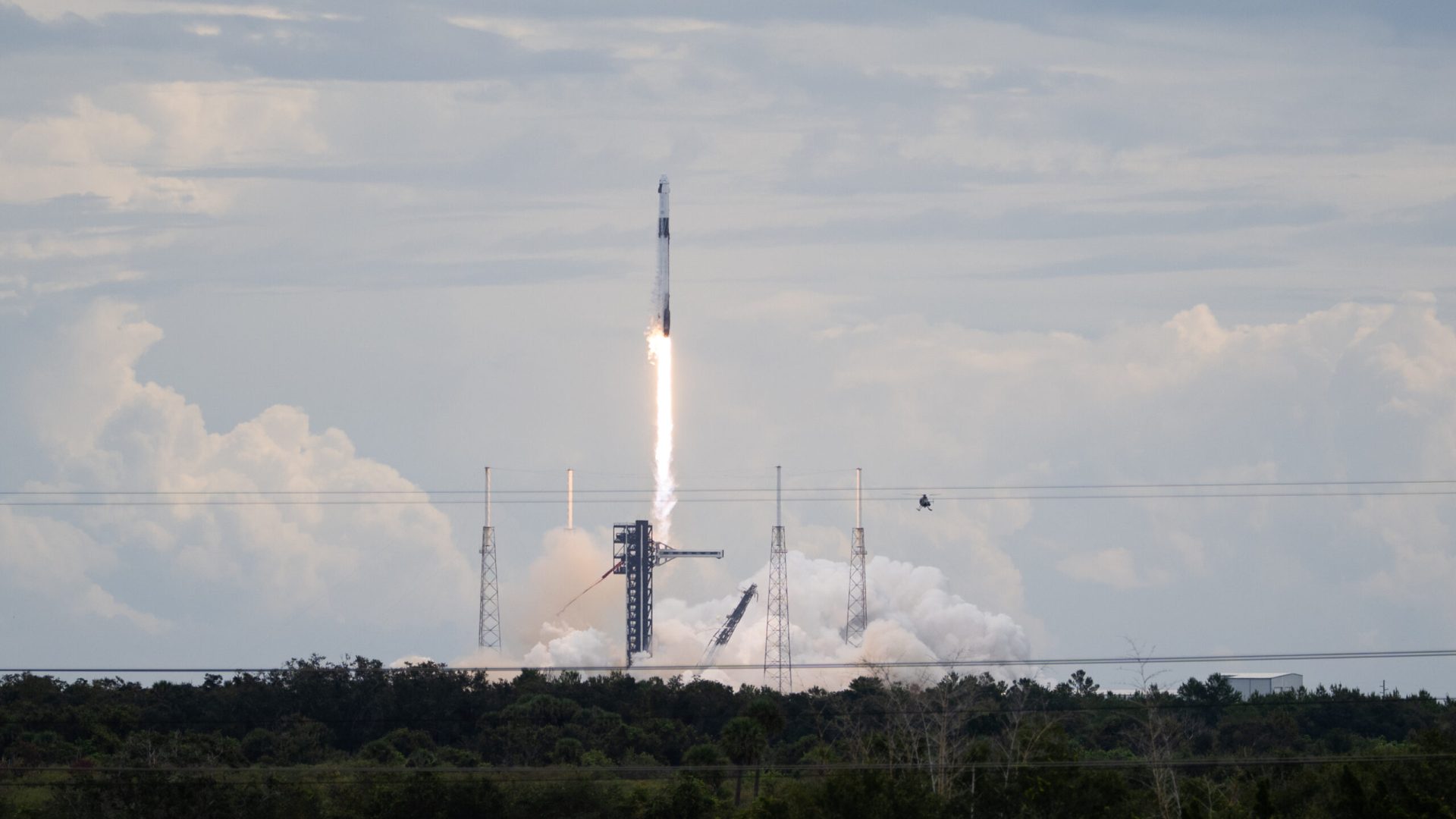 A SpaceX Falcon 9 rocket carrying the company's Dragon spacecraft launches. There is a bright col...