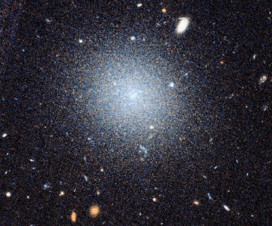 A close-up Hubble image of the galaxy DF9 is shown beneath a wider view of the surrounding NGC 10...