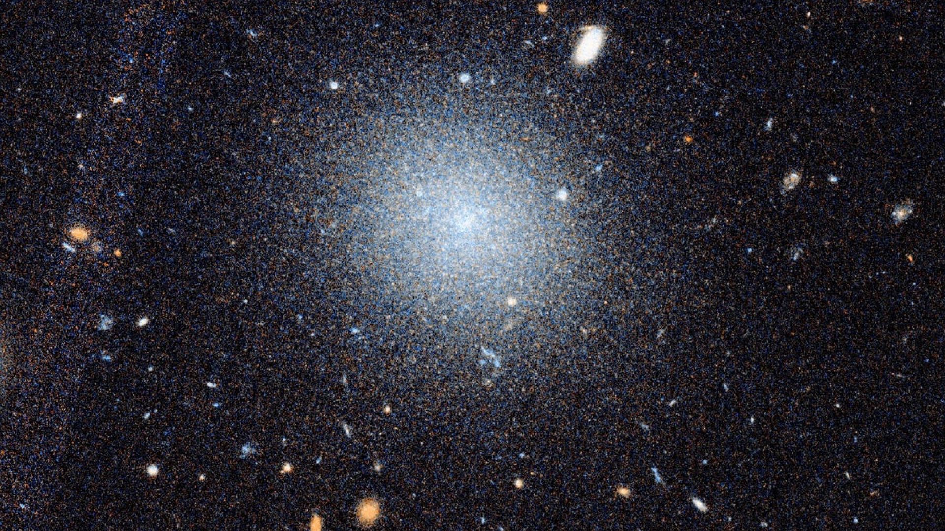 A close-up Hubble image of the galaxy DF9 is shown beneath a wider view of the surrounding NGC 10...