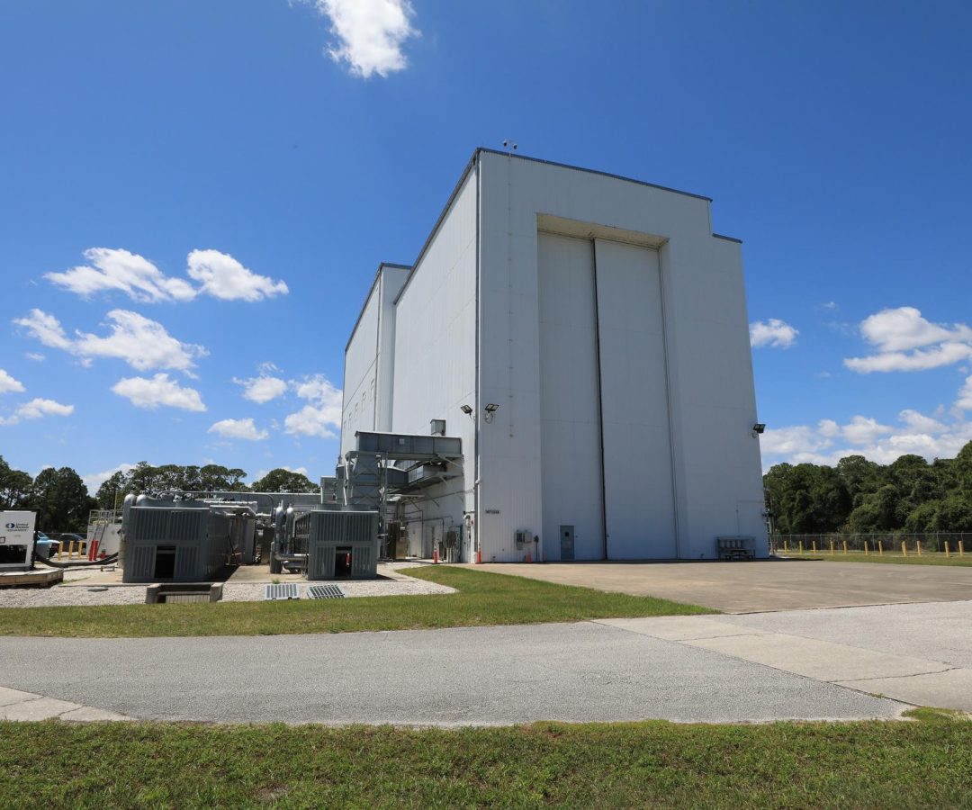 Image shows sunny, blue skies with a few wispy clouds outside the NASA Kennedy’s Payload Hazard...