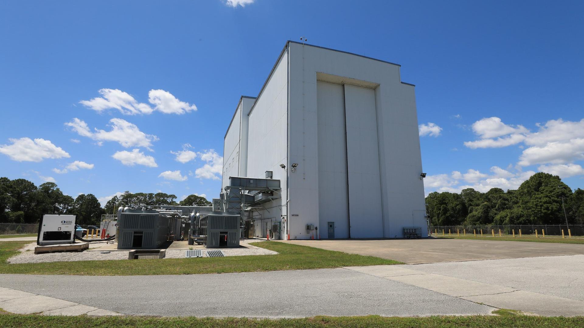 Image shows sunny, blue skies with a few wispy clouds outside the NASA Kennedy’s Payload Hazard...